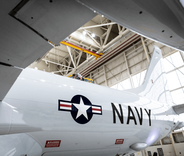Mechanic on top of an airplane in a hangar
