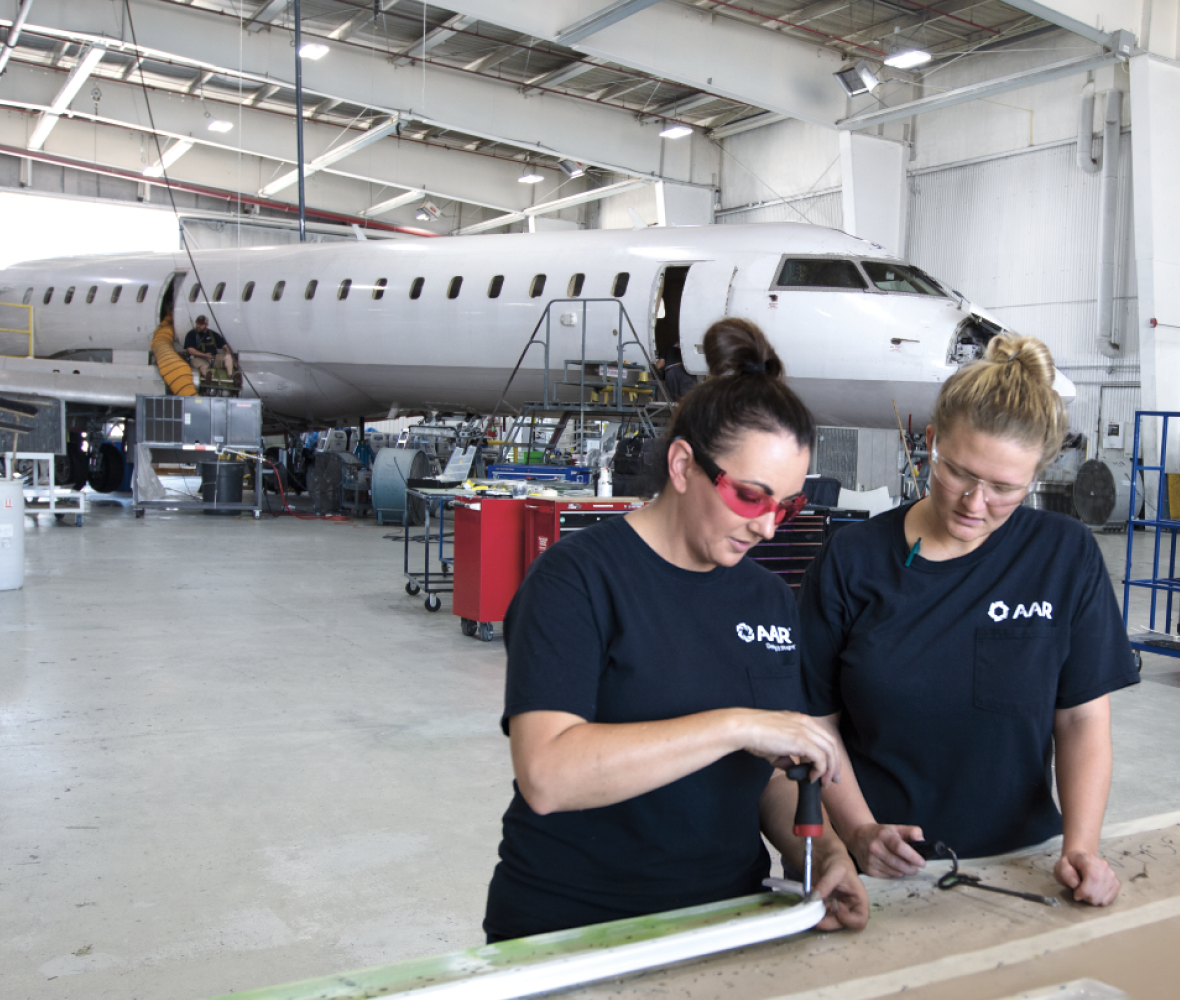 Two mechanics standing in front of an airplane