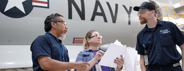 Employees in front of a Navy plane